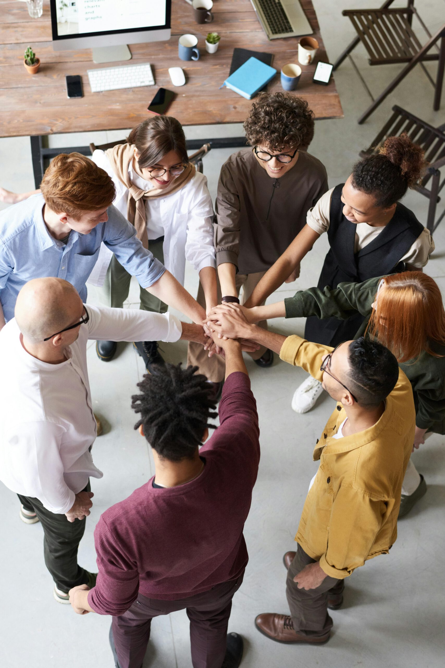 8 personnes heureuses en cercle mettant leurs main l'une au dessus de l'autre